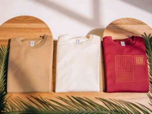 Flat lay of tan, white, and red sweatshirts with minimal graphic prints