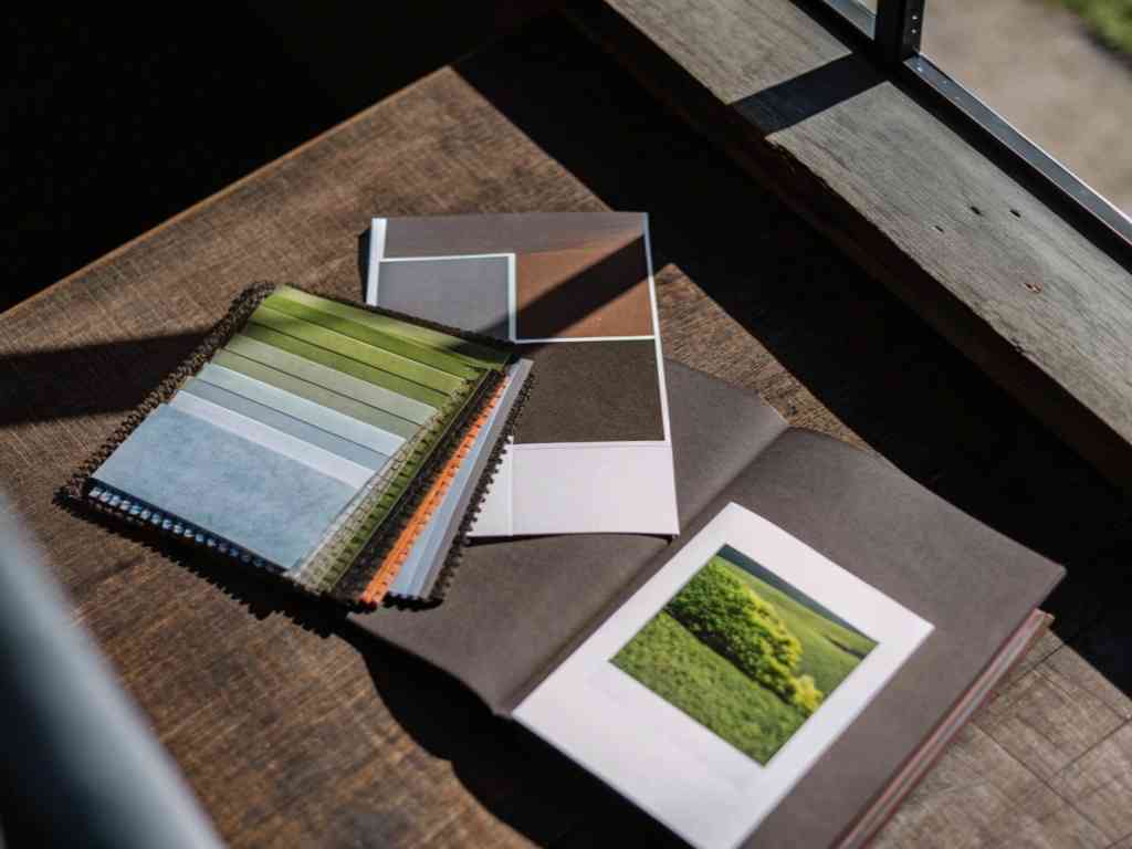 Open book with fabric swatches and nature-inspired color palettes near a window.