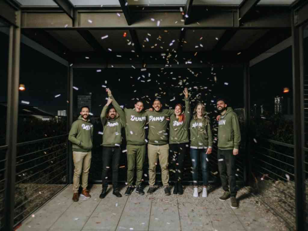 Group in green hoodies celebrating under confetti at night