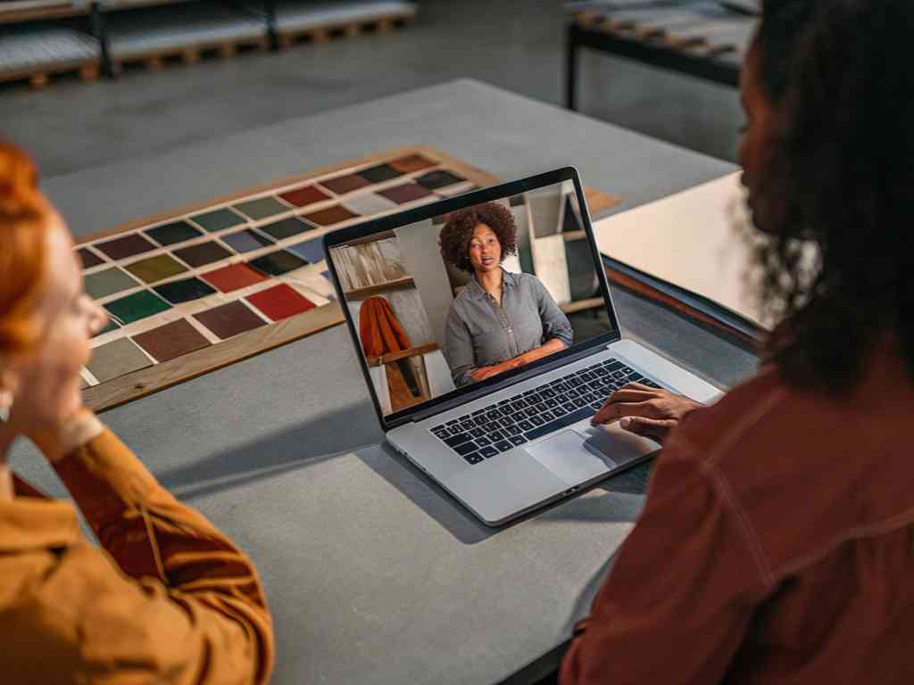 Two women in virtual meeting with fashion consultant on laptop.