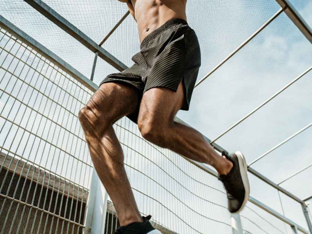 Man jumping in lightweight black mesh running shorts on metal stairs