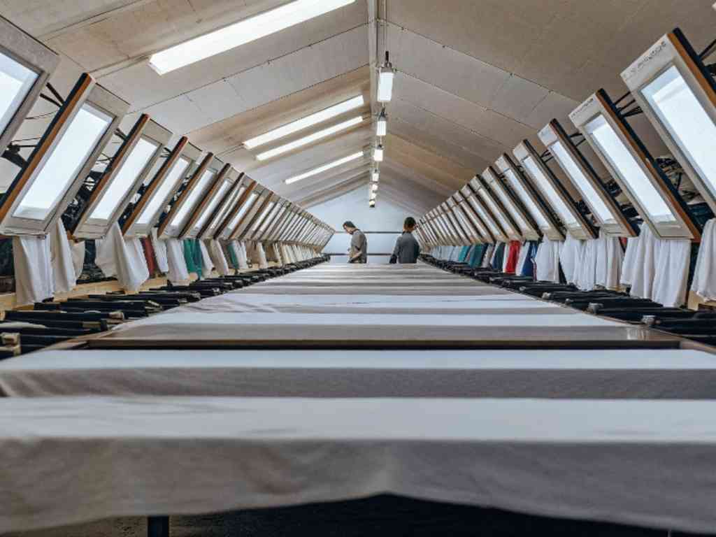 Long textile production line with aligned screens and hanging garments.