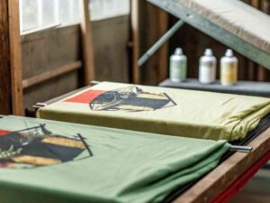 Freshly screen-printed green T-shirts with graphic designs drying in a studio.