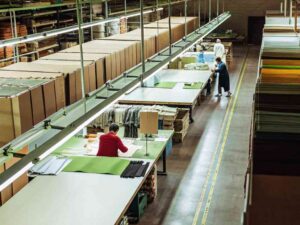 Workers in modern textile factory working with fabric on long tables