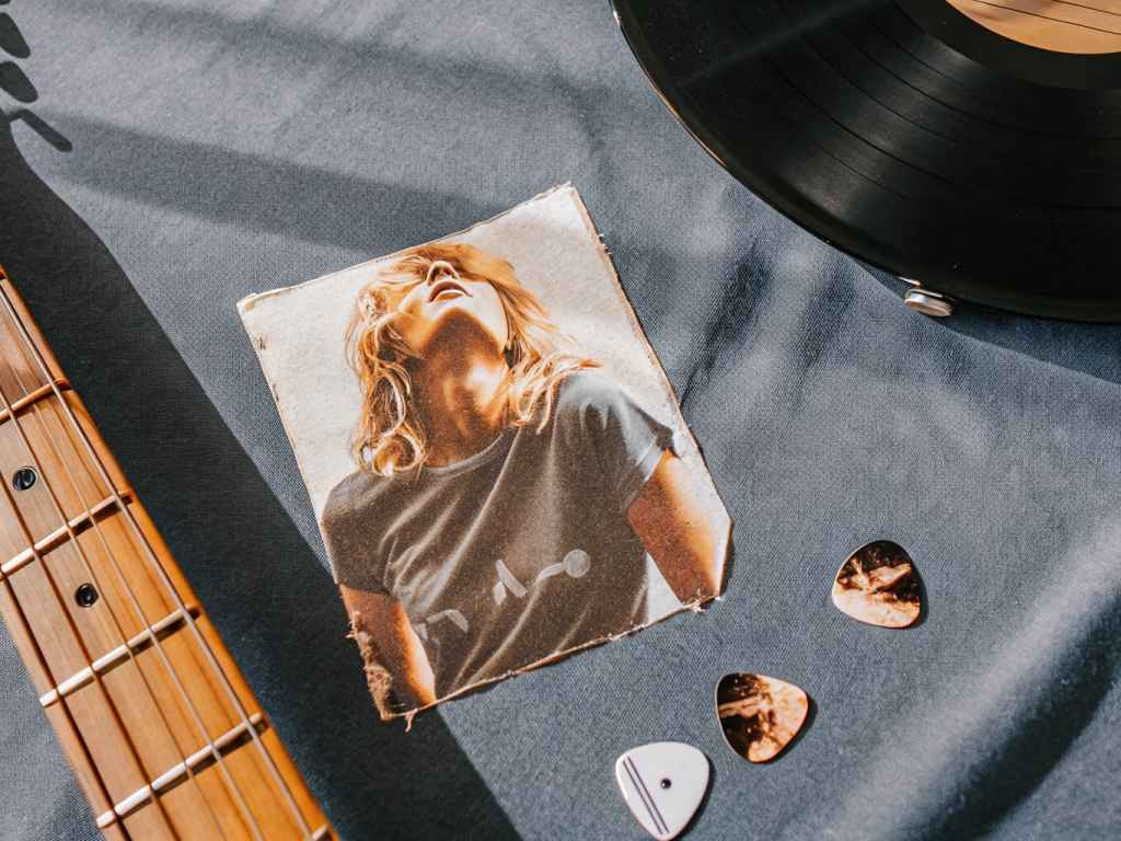 Flat lay with vintage photo, guitar, record, and picks.