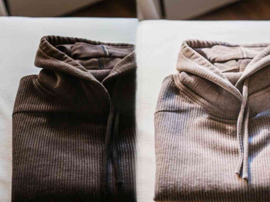 Ribbed brown and beige hoodies folded flat on fabric surface