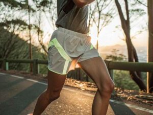 Athlete running at sunrise in reflective shorts on mountain road