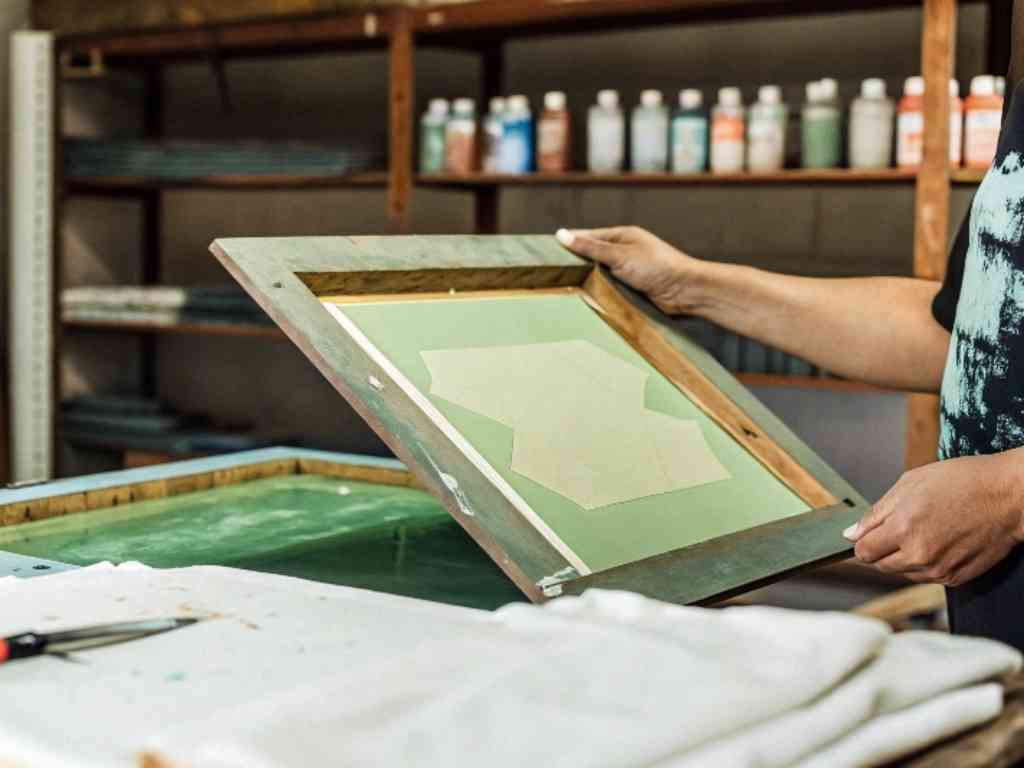 Person aligning screen printing frame over fabric in workshop