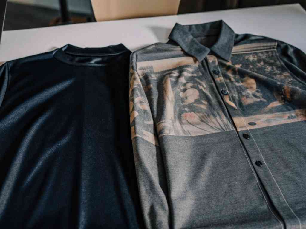 Two shirts on a table, one plain black and one with a printed design.