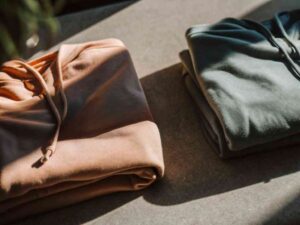 Folded peach and green hoodies side by side in natural light