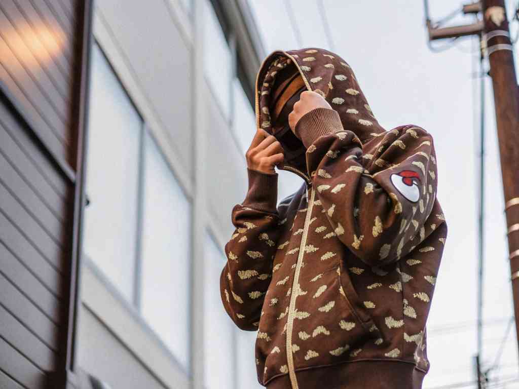 Model in brown BAPE shark hoodie with zipper up and hood pulled tight.