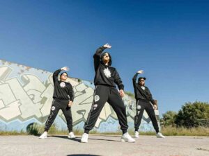 Group of dancers in matching black tracksuits performing outdoors
