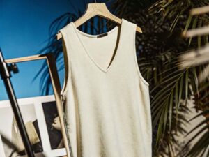 Ivory knit v-neck tank top hanging in studio setup.