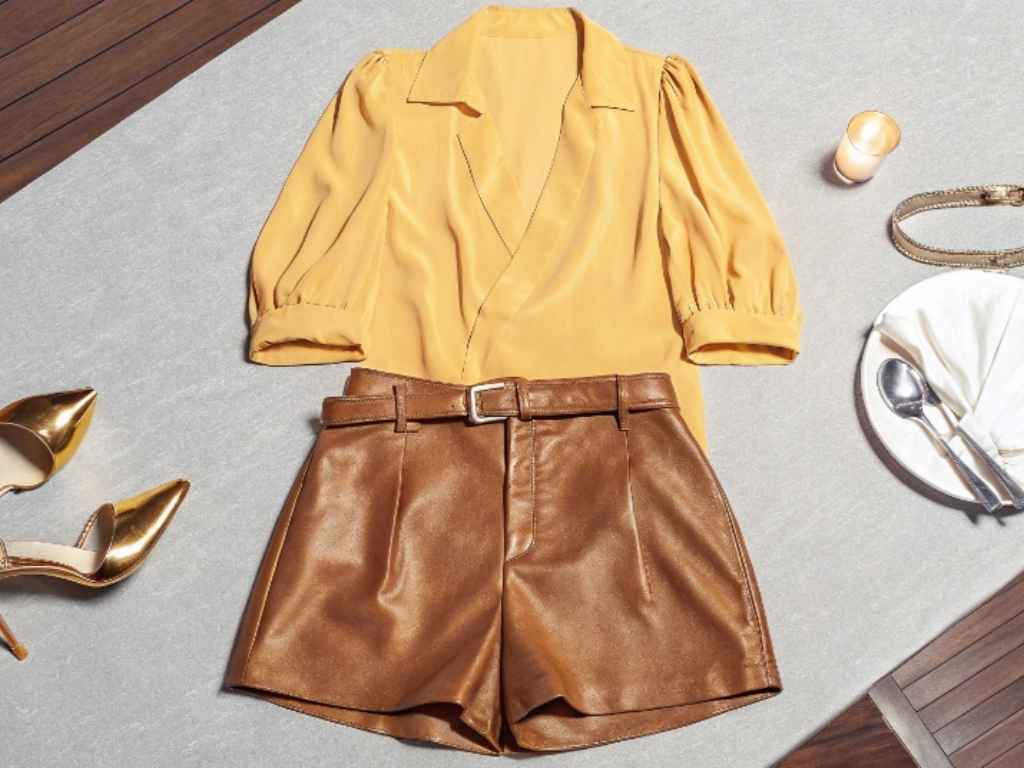 Brown leather shorts styled with yellow blouse and gold heels for dinner