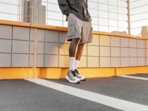 Man in gray cargo shorts and white sneakers on rooftop at golden hour