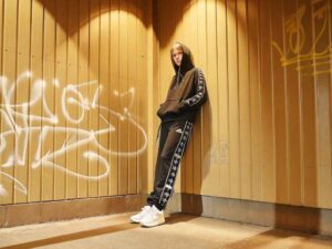 Model in hooded tracksuit with white graphics in gritty urban setting