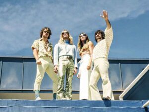 Group in 70s-inspired fashion posing under sunny sky.