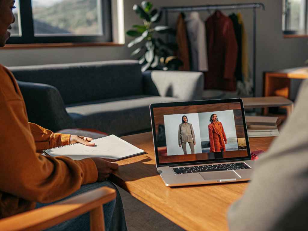 Designers reviewing fashion lookbook on laptop during team meeting