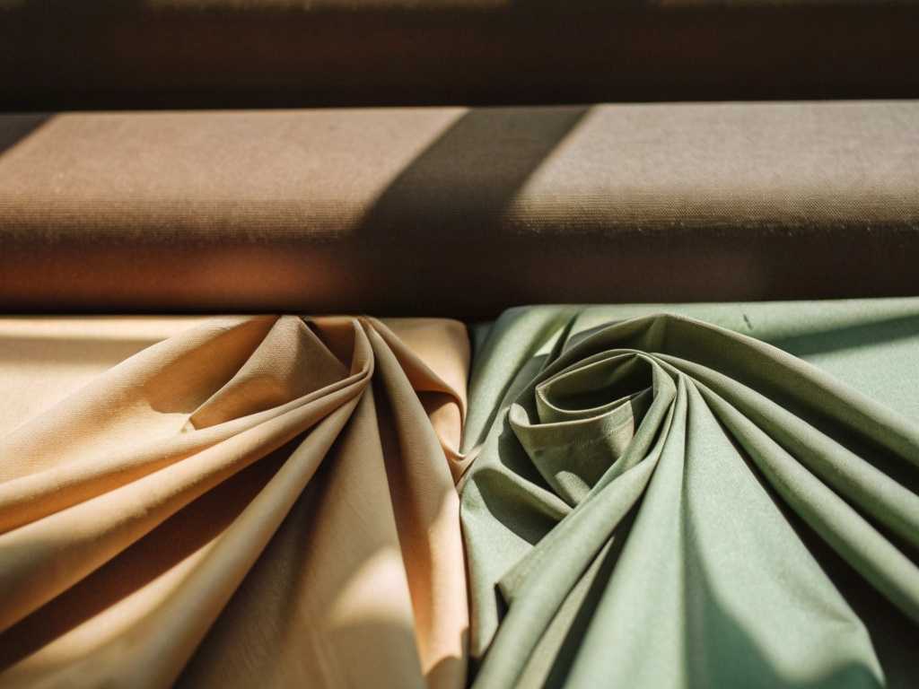 Artistic display of beige and green fabric rolls arranged neatly.