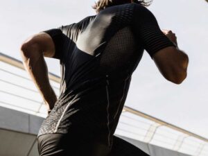 Rear view of runner sprinting in black mesh performance shirt