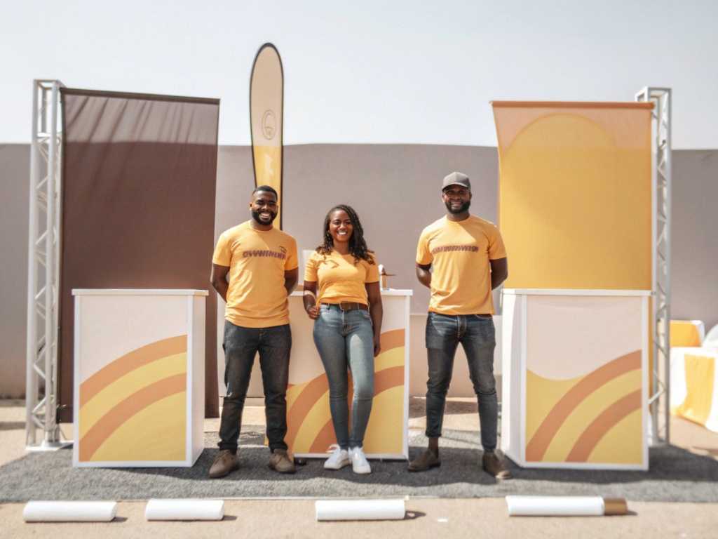 Three staff in matching orange branded T-shirts at pop-up booth