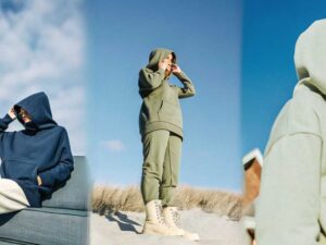 Women in hoodies by the coast styled in navy, sage, and olive under blue sky