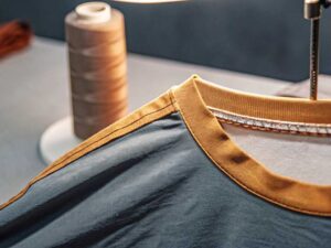 Close-up of mustard rib neckline stitched onto slate blue tee
