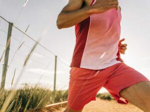 Runner in coral mesh singlet and shorts on sunny trail
