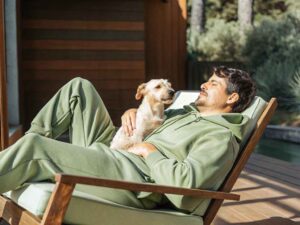 Man in green hoodie relaxing on chair with dog