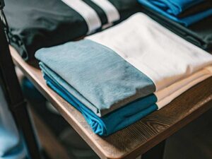 Neatly stacked blue, grey and white color-blocked shirts on table