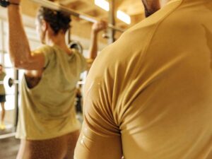 Sweaty athletes lifting barbell wearing mustard and olive workout shirts