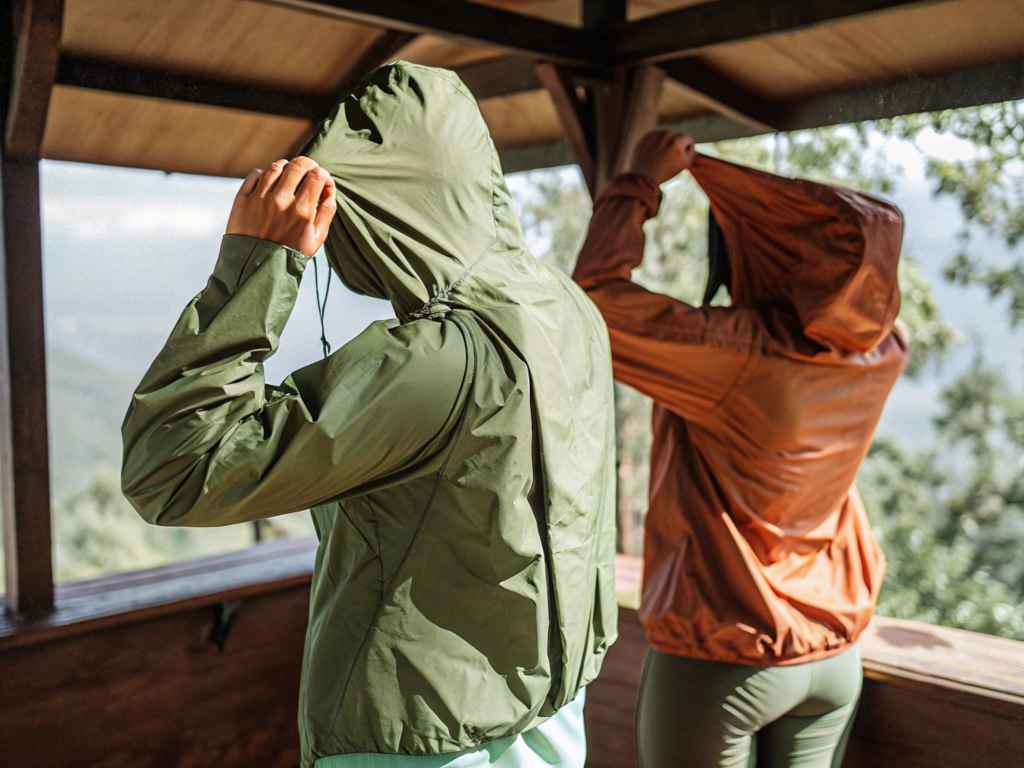 Two hikers tightening hoods on lightweight jackets in shelter mountain