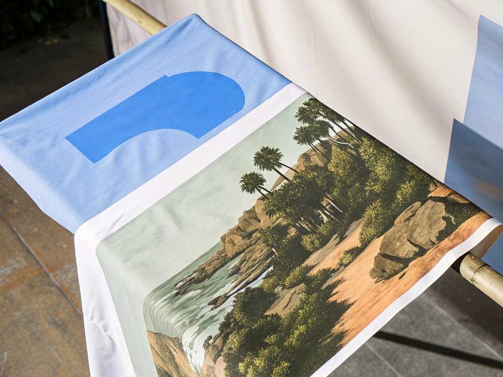 Fabric printed with scenic nature landscape drying on rack.
