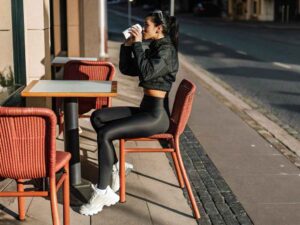 Woman in black athleisure sipping coffee at outdoor cafe