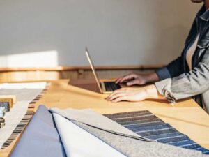 Laptop and blue-toned textile samples under warm daylight