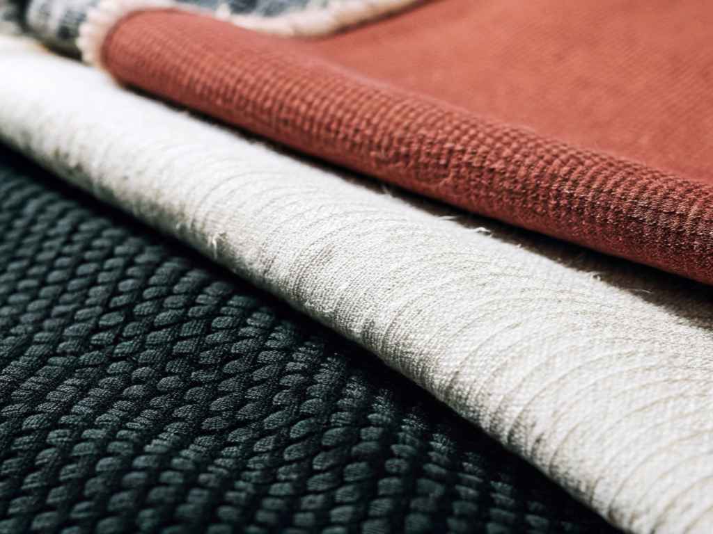 Layered green, ivory and terracotta textured fabrics close-up