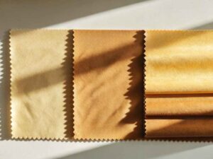 Four golden fabric swatches lit by angled sunlight