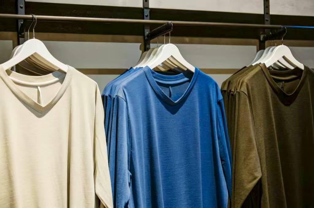 Neutral, blue, and olive V-neck shirts on white hangers