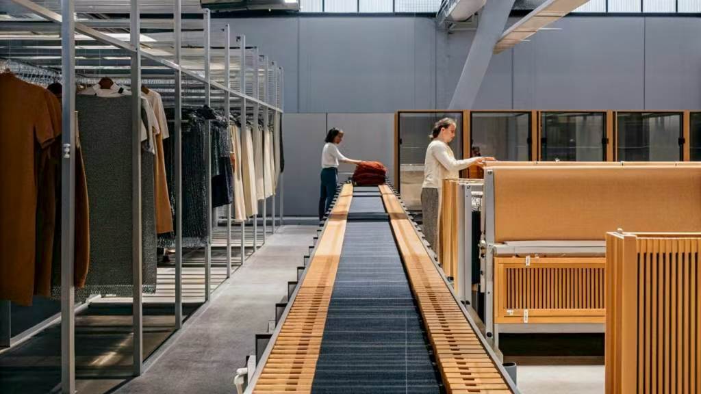Workers organizing garments on shelves and conveyor system in warehouse