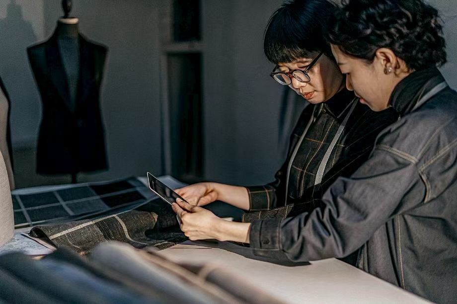 Two designers reviewing fabric samples on table.