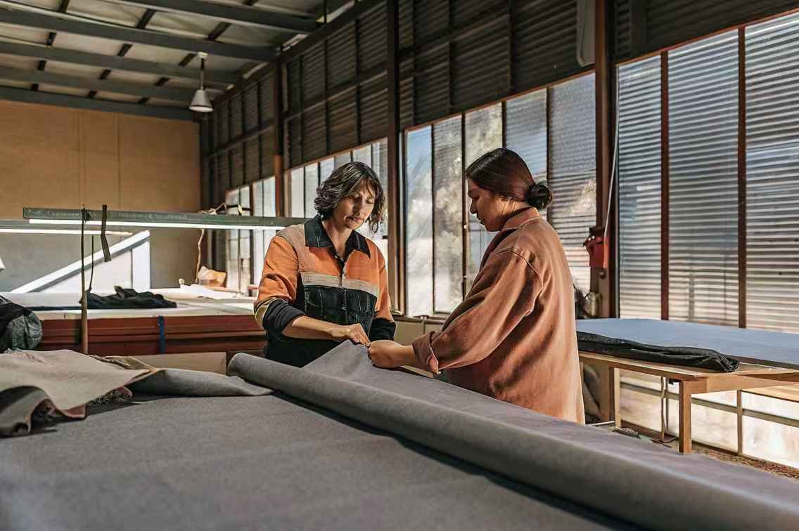Two women inspecting fabric in workshop.