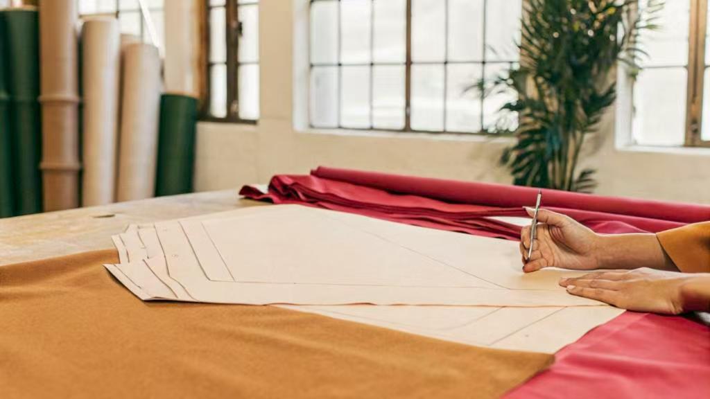 Hands tracing garment pattern on fabric