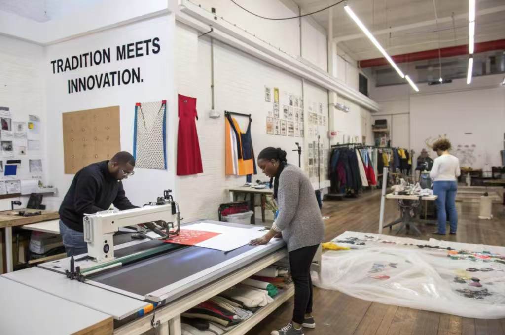 Designers working in a creative garment studio with innovation signage.