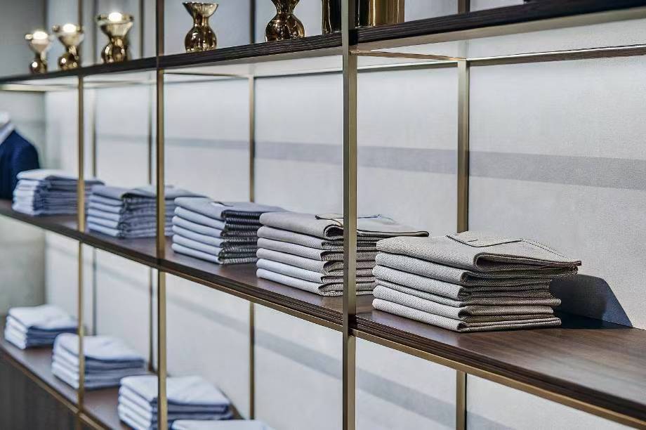 Neatly stacked folded dress shirts on modern retail shelves.