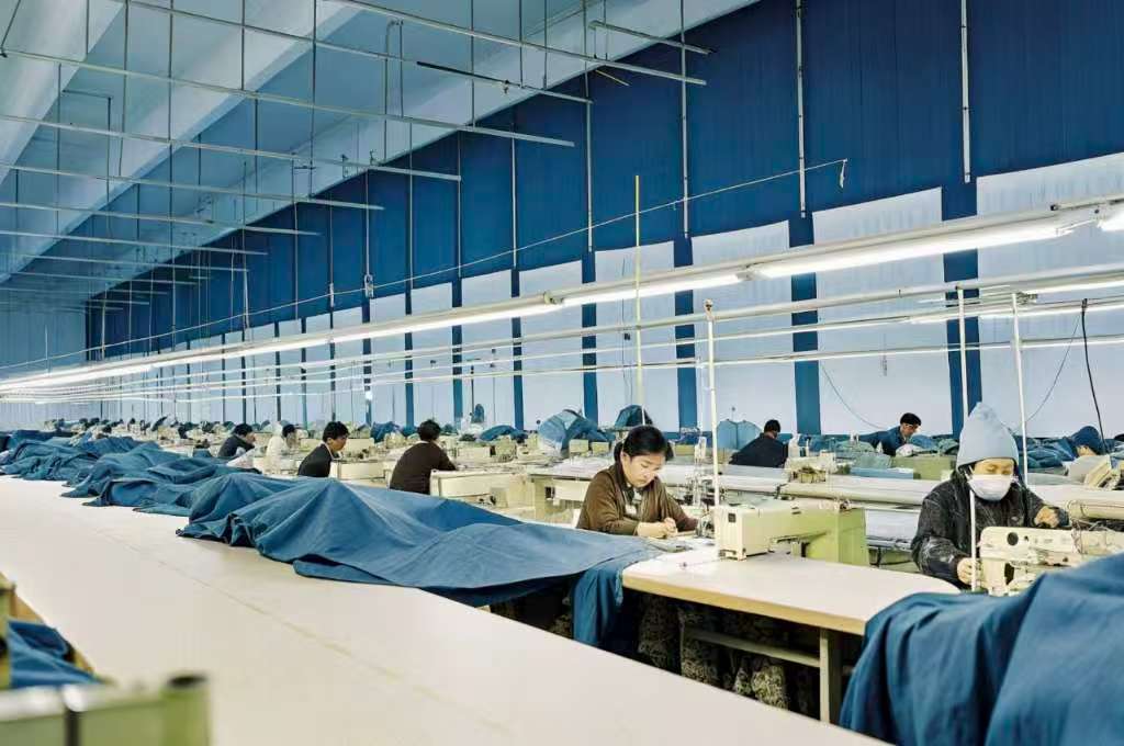 Workers sewing garments in a large-scale textile factory.