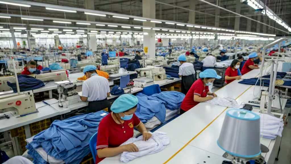 Workers sewing clothes in a large garment manufacturing factory