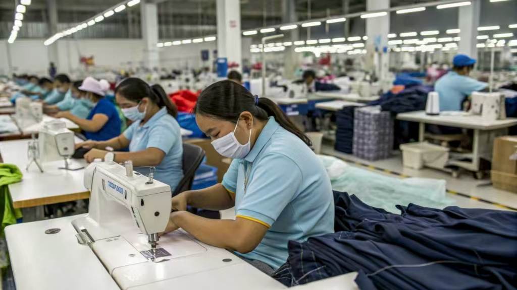 Workers sewing clothes on machines in a garment factory.