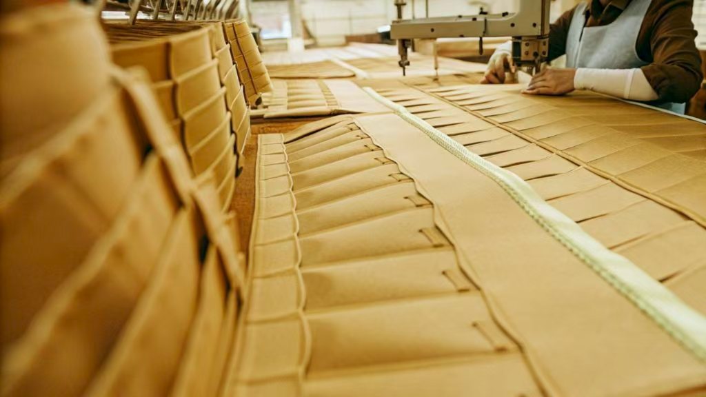 Worker stitching heavy fabric on industrial sewing machine