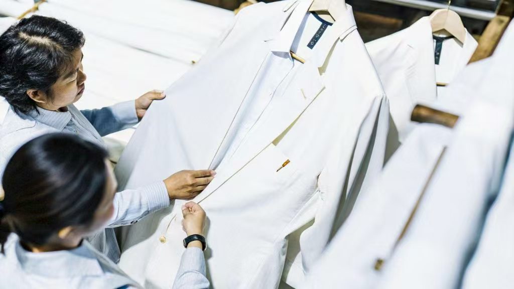 Two people examining a white suit jacket in a clothing store