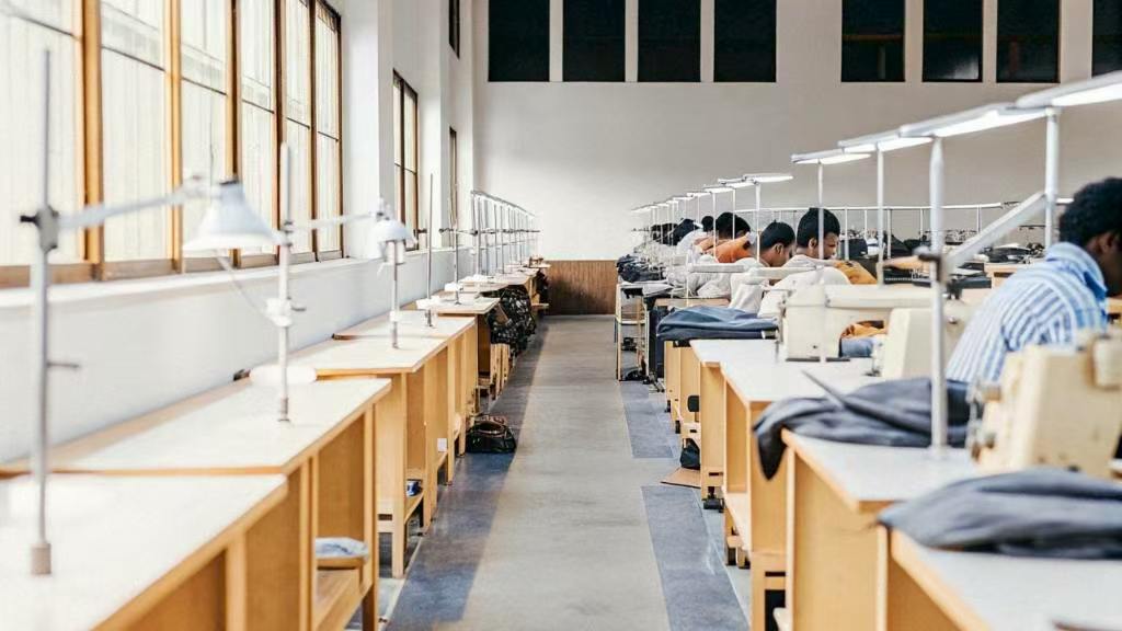 Workers sewing garments at bright factory workstations